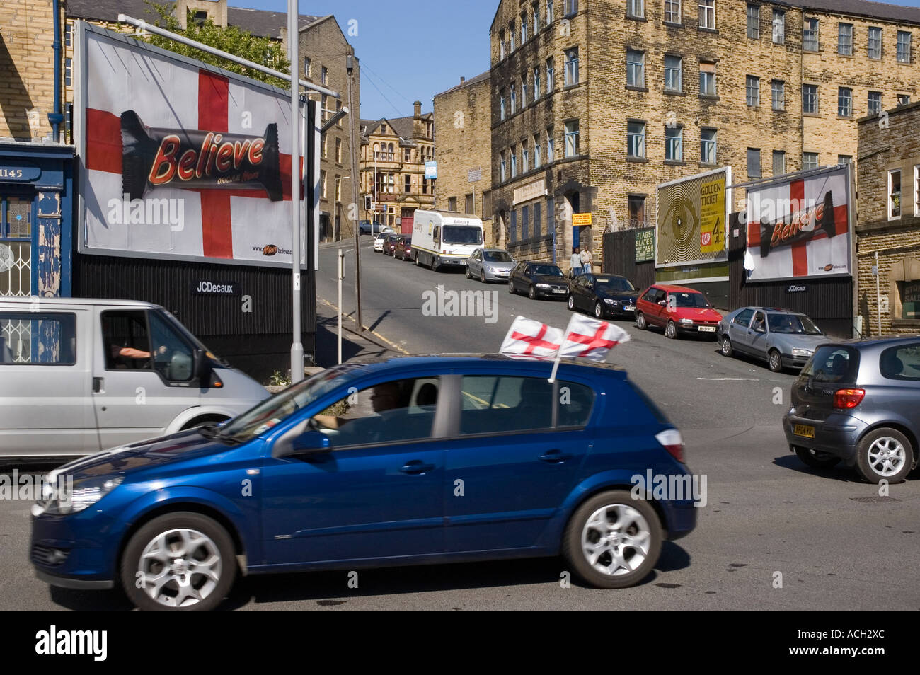 An car with two England flags driving past two roadside advertisements