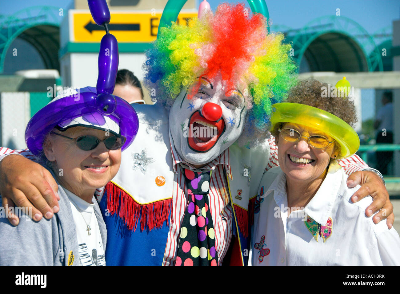 A clown in full colorful costume posing with two senior citizens at the Red River Exhibition in Winnipeg Manitoba Canada Stock Photo