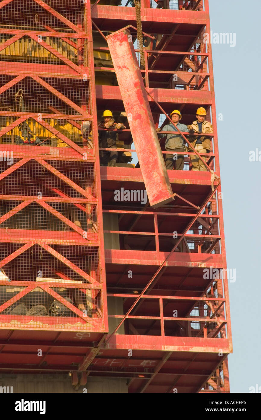 Construction workers hoist steel beam on to bridge building Stock Photo