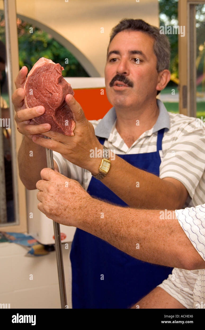 Man prepares large chunk of meat on espeto skewer for Barbecue in