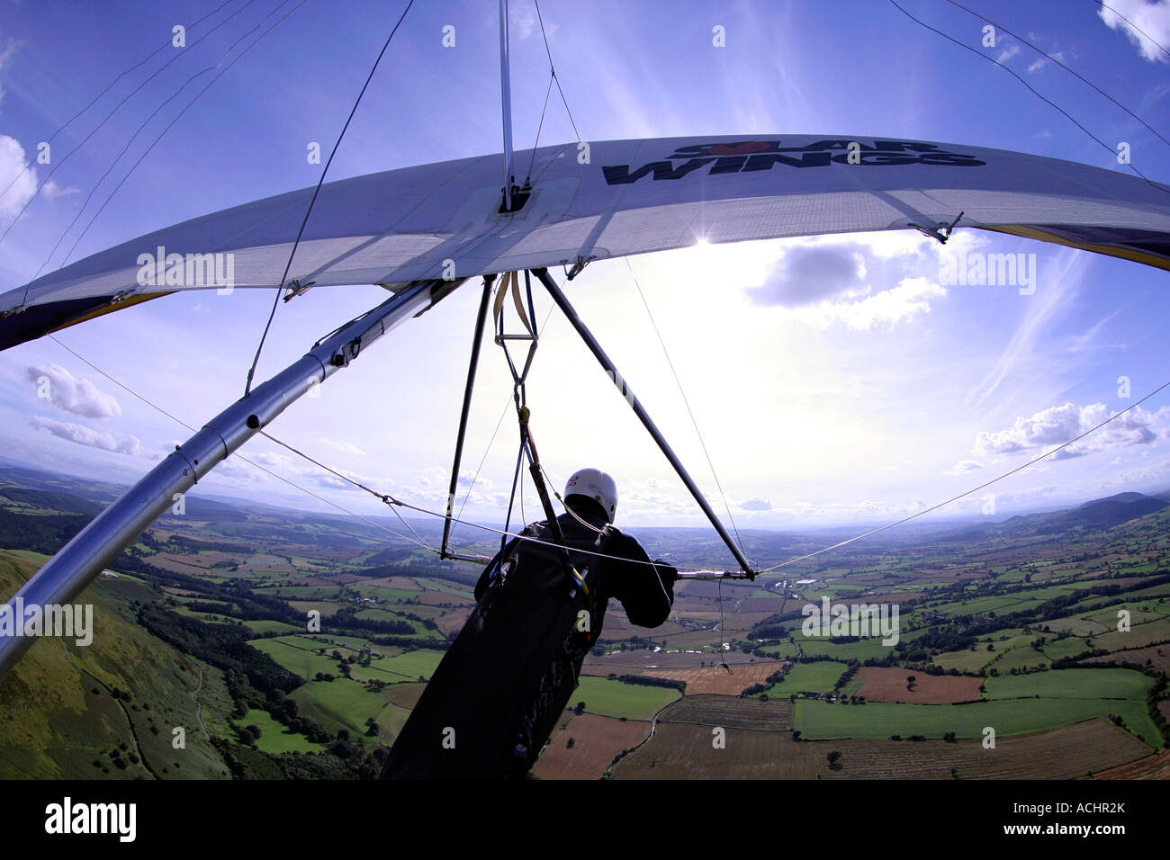 In flight shot of a hang glider flying into the sun over the Long Mynd