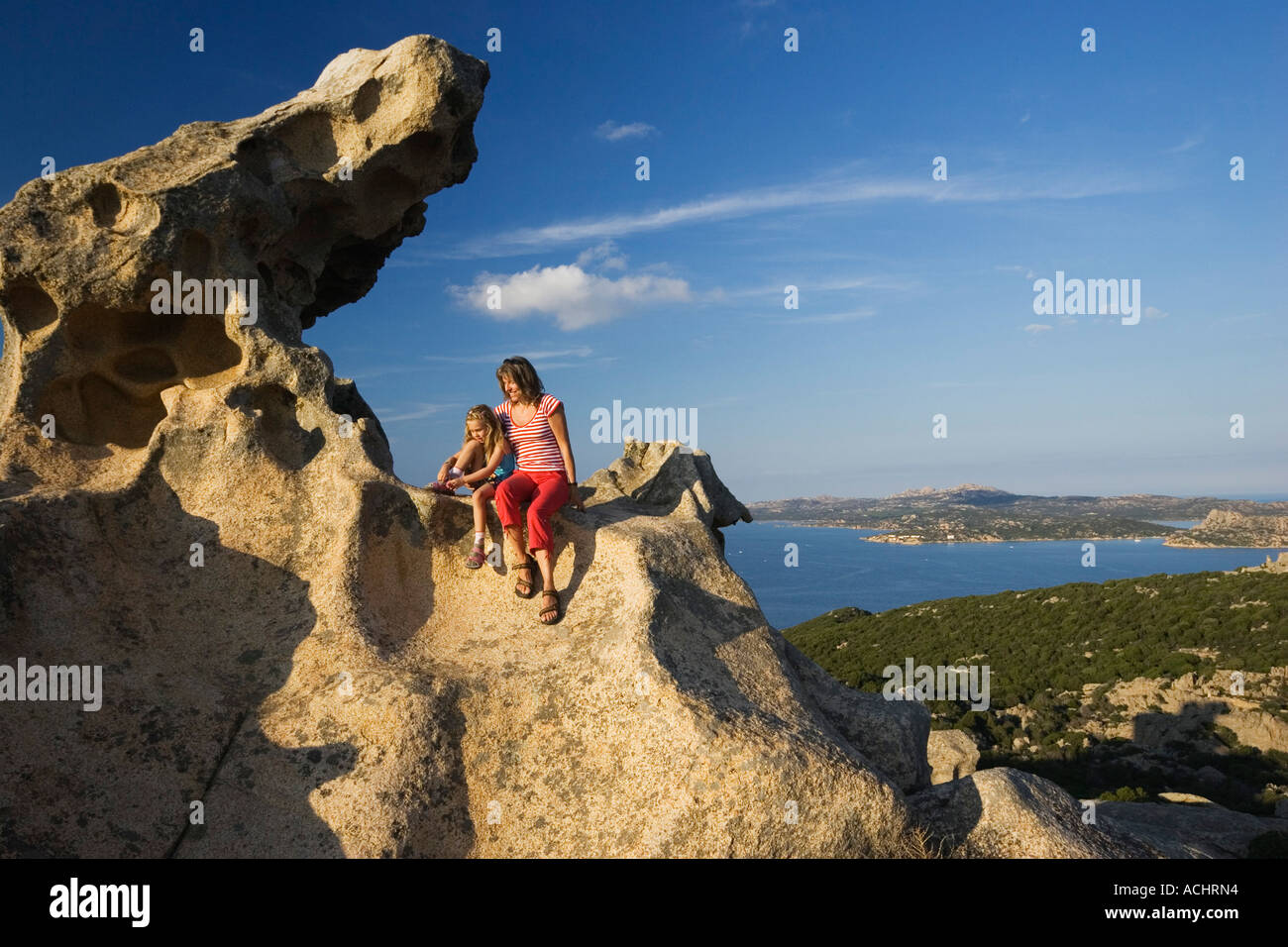 Mother and daughter on rock, Capo d'Orso, Sardinia, Italy Stock Photo