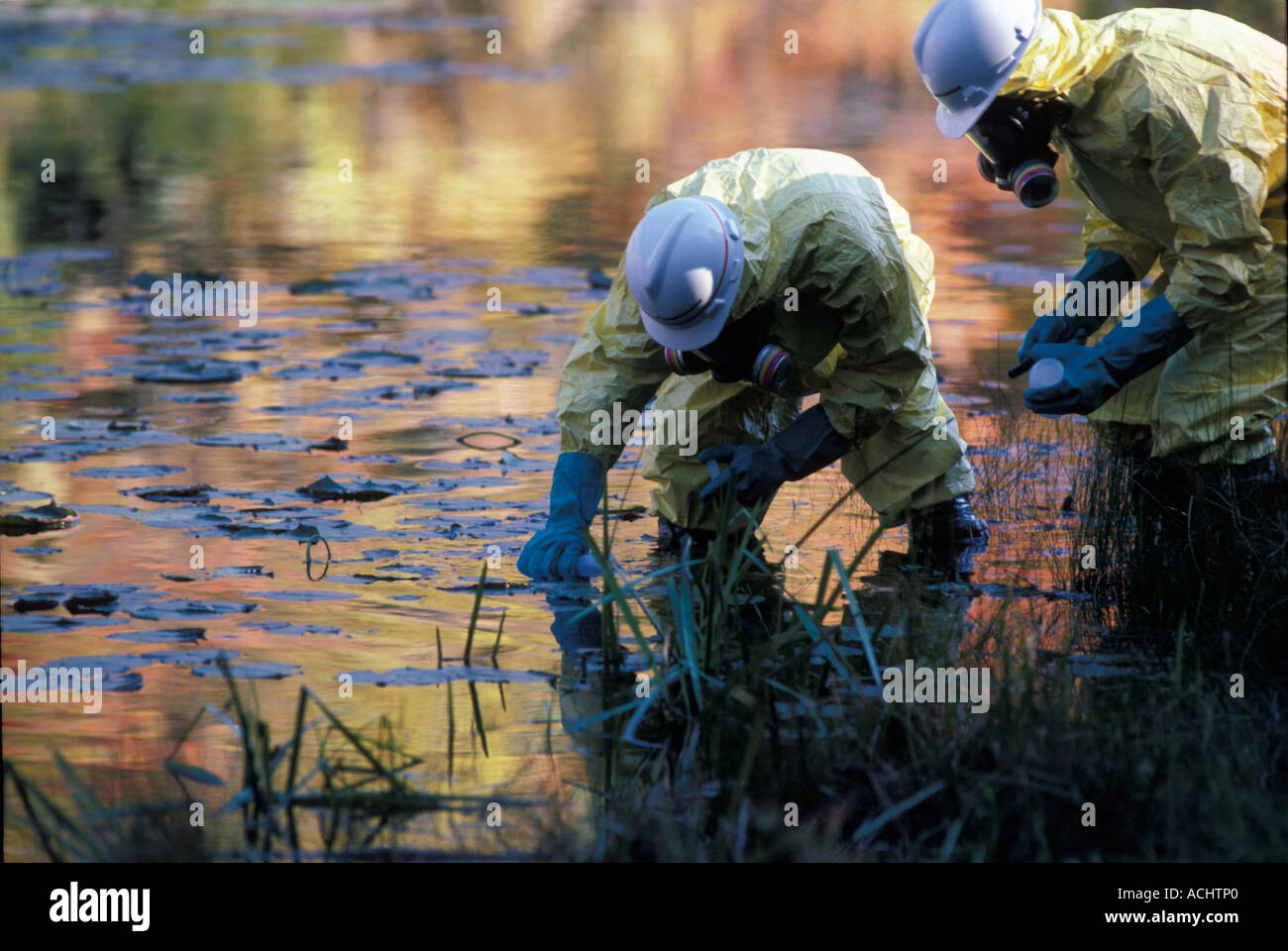 Environmental technicians in protective clothing testing polluted water Stock Photo