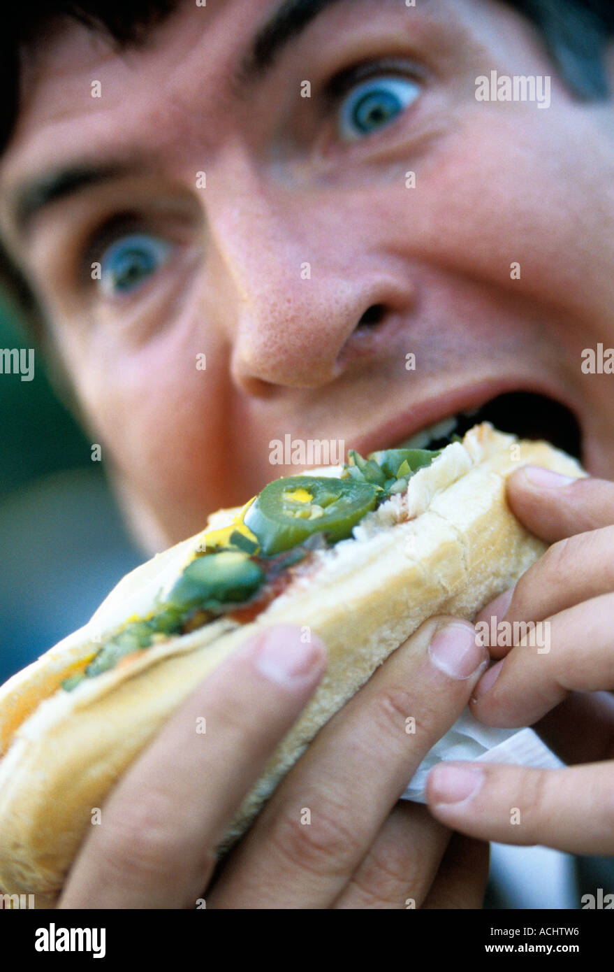 Caucasian man eating hot dog with hot peppers Stock Photo