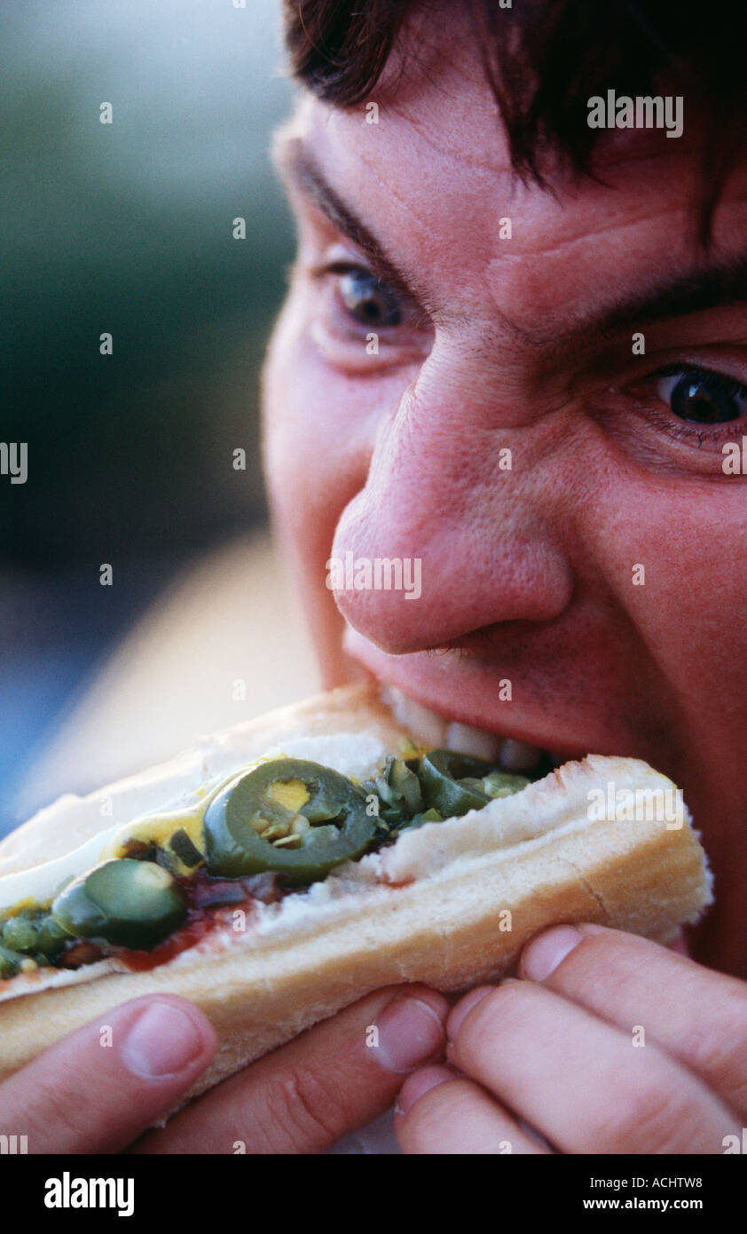 caucasian man eating hot dog with hot peppers Stock Photo