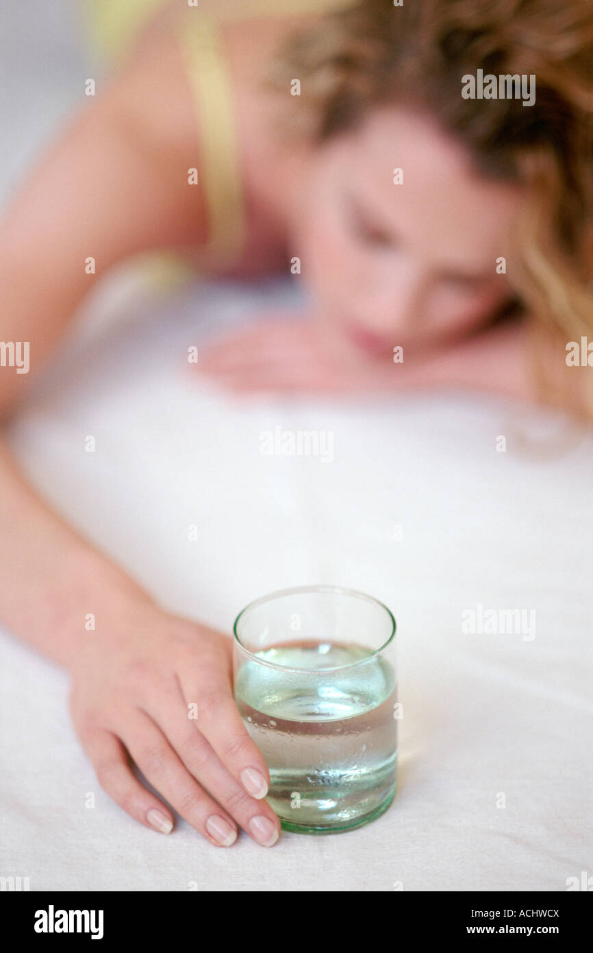 Woman lying down on the floor holding glass of water Stock Photo - Alamy