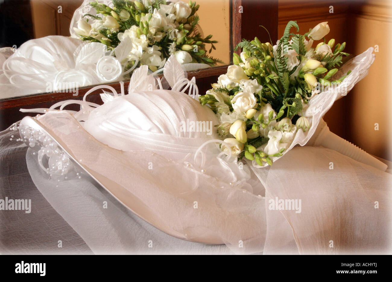 A portrait of a white traditional wedding dress pictured here in a presentation box with a bouquet of flowers on top of it. Stock Photo