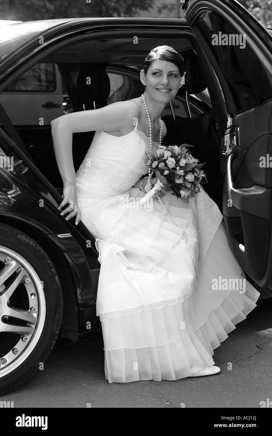 Bride on her wedding day getting out of wedding car limousine Stock Photo