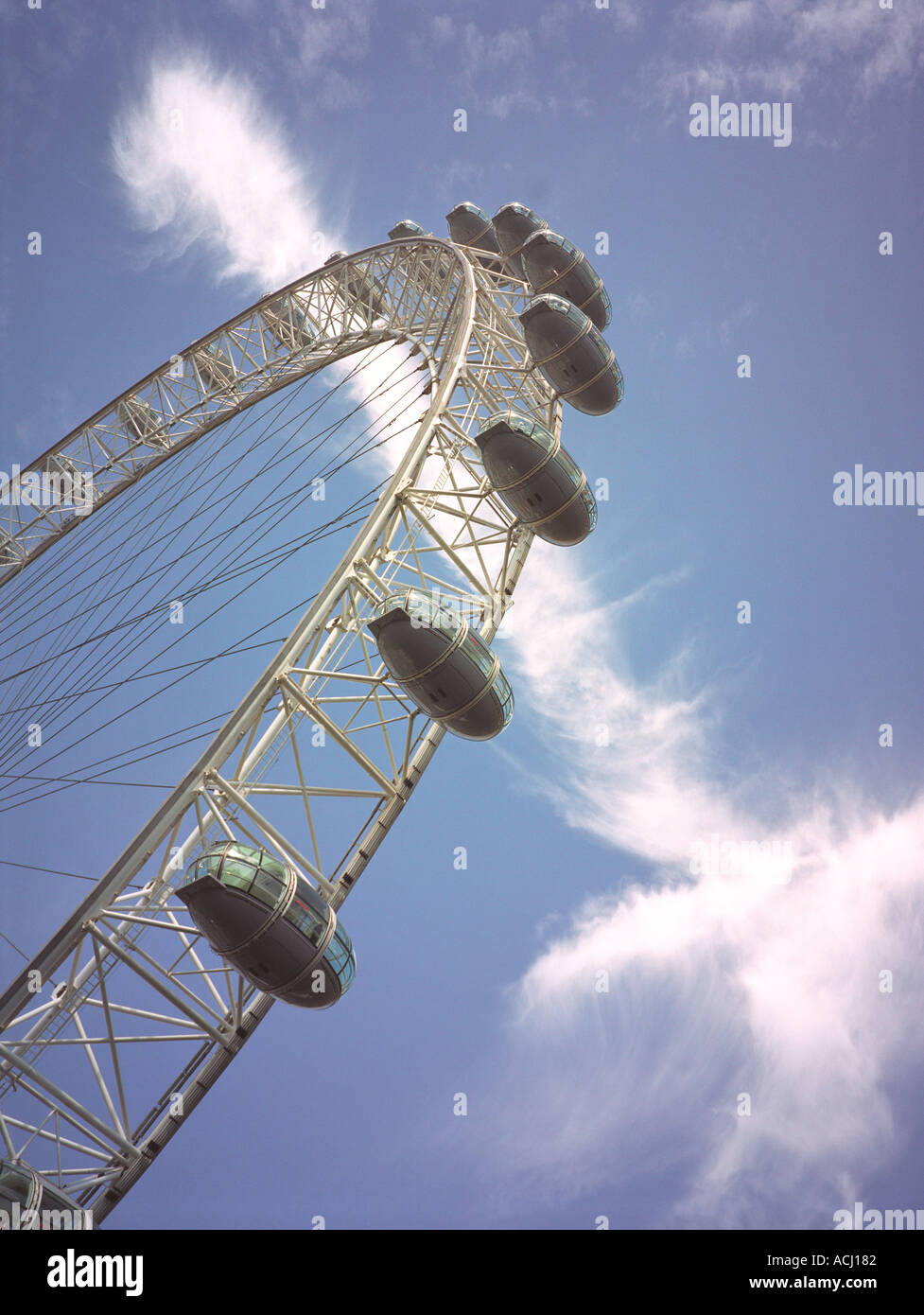 London eye from the ground with blue sky containing airplane trails and the sun Stock Photo