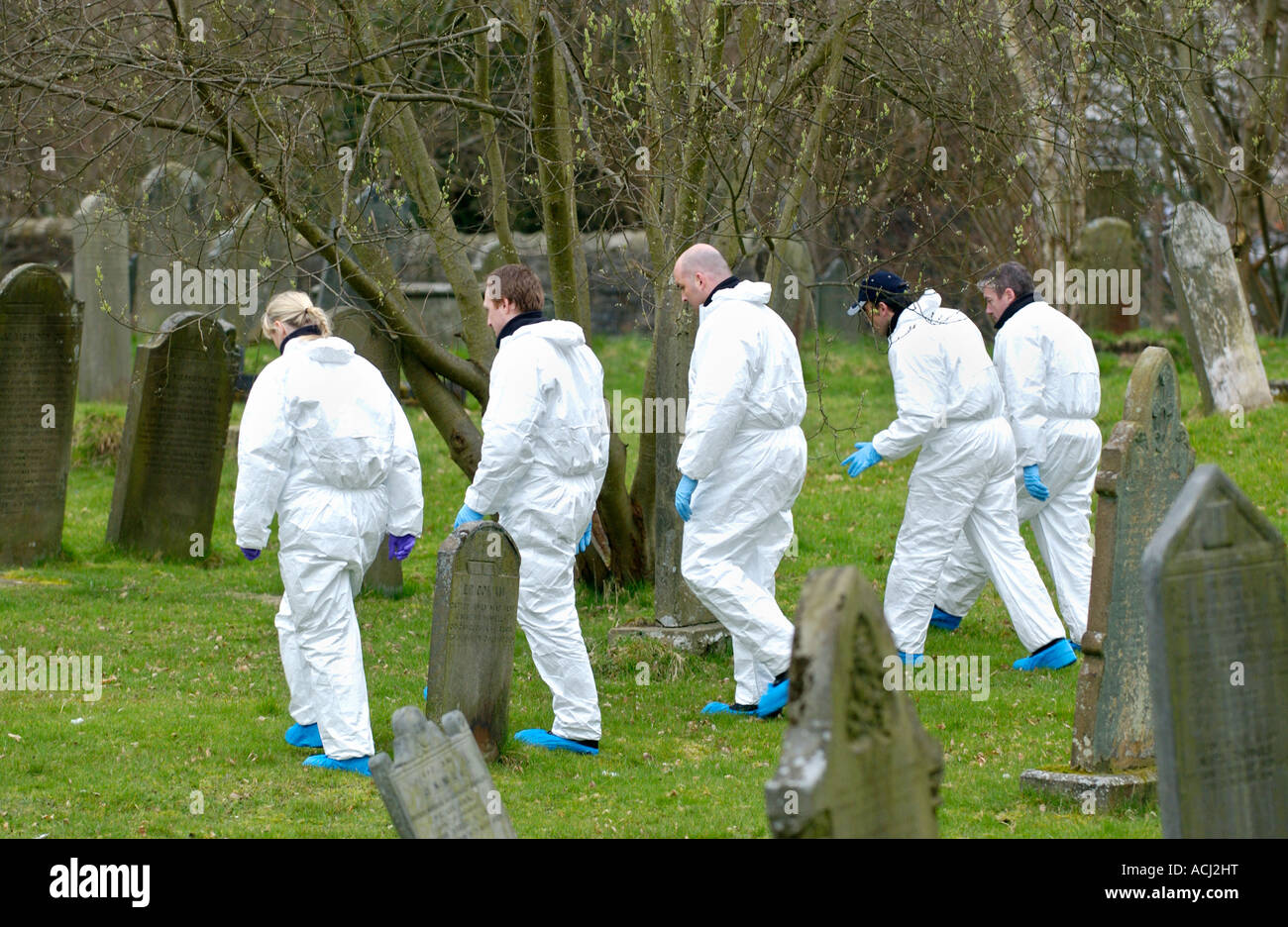 Police officers search graveyard after murder of Father Paul Bennett stabbed to death in the grounds of his church Wales UK Stock Photo