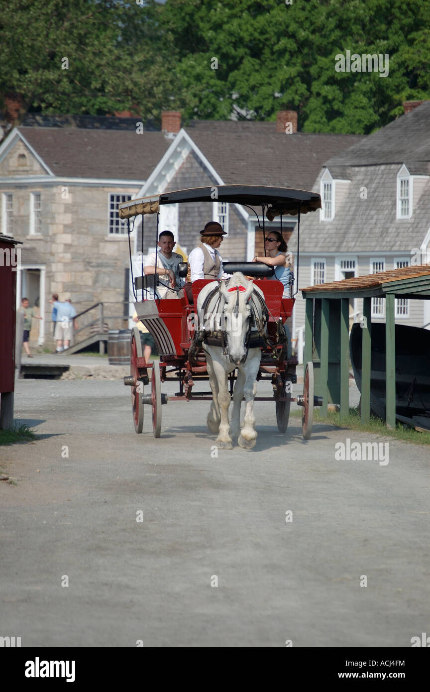 A horse drawn carriage gives tourists rides at Mystic Seaport in Connecticut Stock Photo