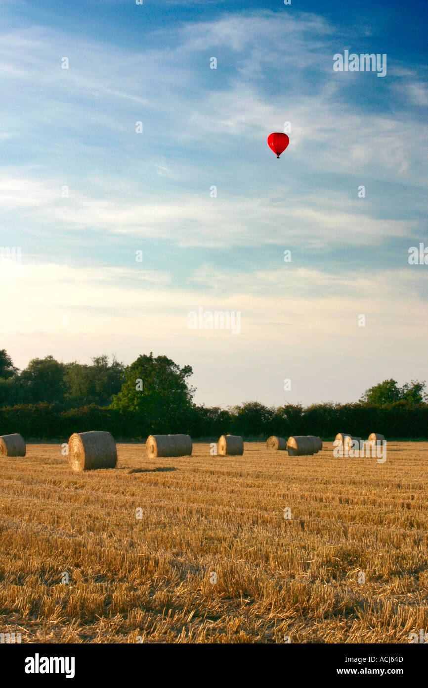 Hot air ballon over straw bails in summer. Stock Photo