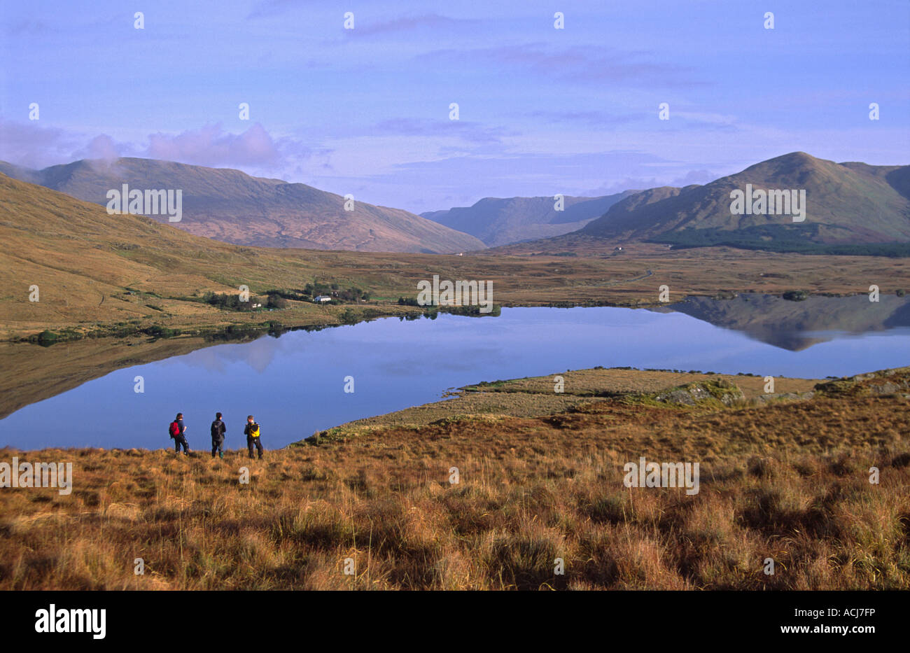 Hikers looking across Lough Fee to the Maumturk Mountains, Connemara, County Galway, Ireland. Stock Photo