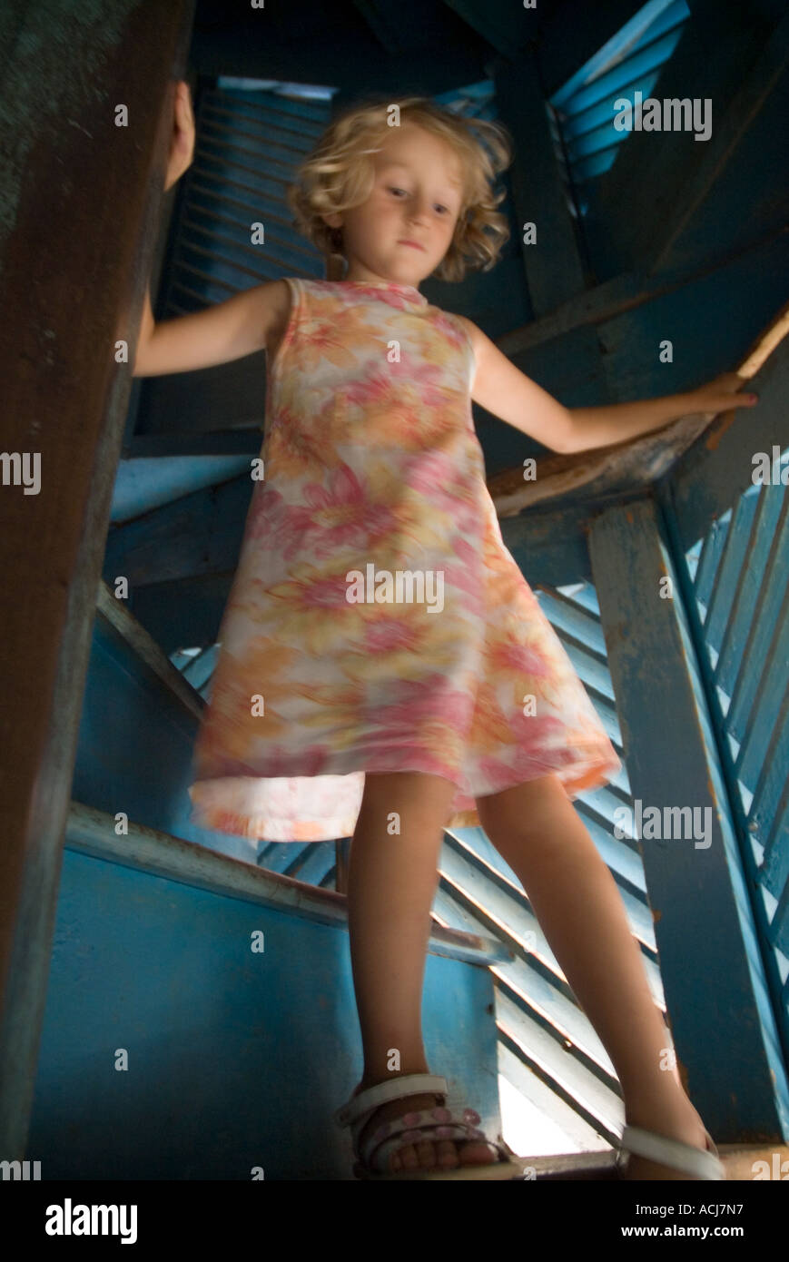 Little blond girl climbing down a spiral staircase, Trinidad, Cuba. Stock Photo