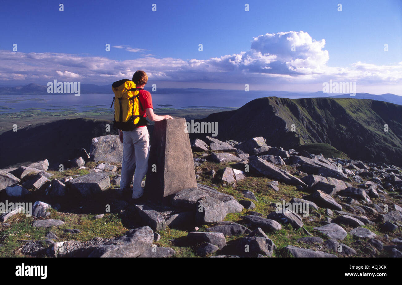 Walker beside the summit cairn of Glennamong mountain, Nephin Beg Mountains, County Mayo, Ireland. Stock Photo