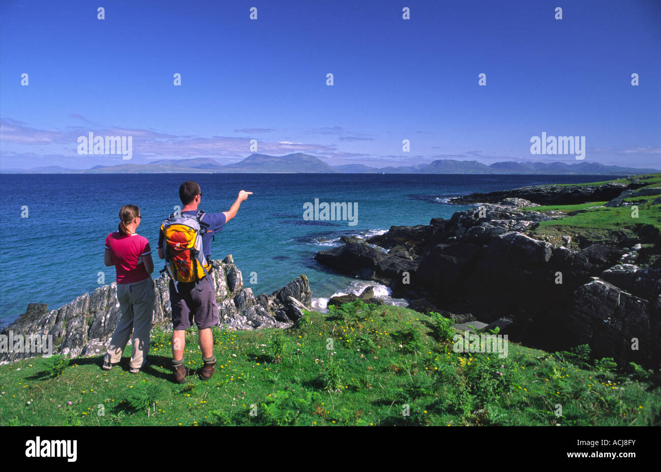 Summer coastal walkers looking towards the mainland from Inishturk Island, County Mayo, Ireland. Stock Photo
