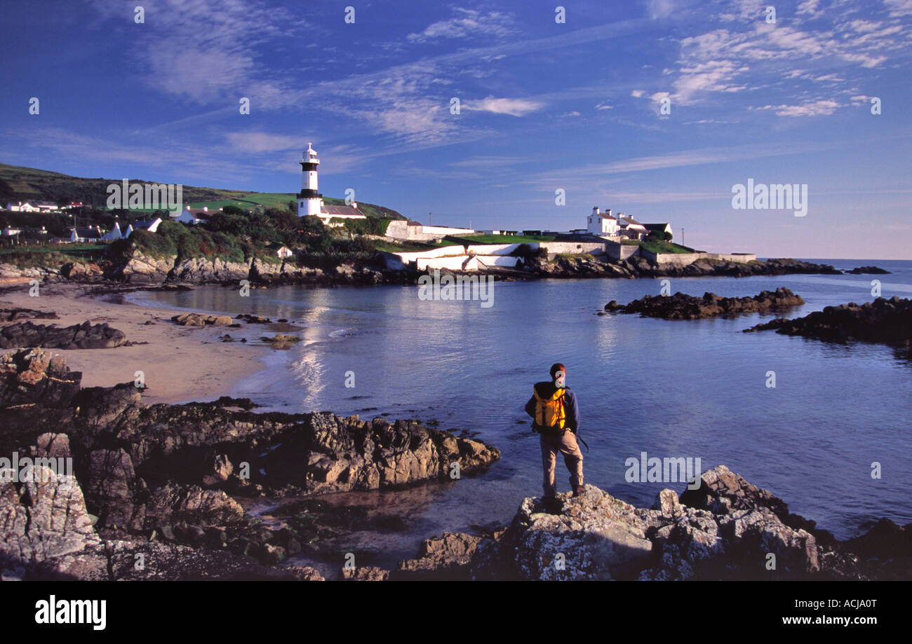 Walker looking across the bay to Inishowen Lighthouse, at Dunagree Point. Inishowen Peninsula, County Donegal, Ireland. Stock Photo