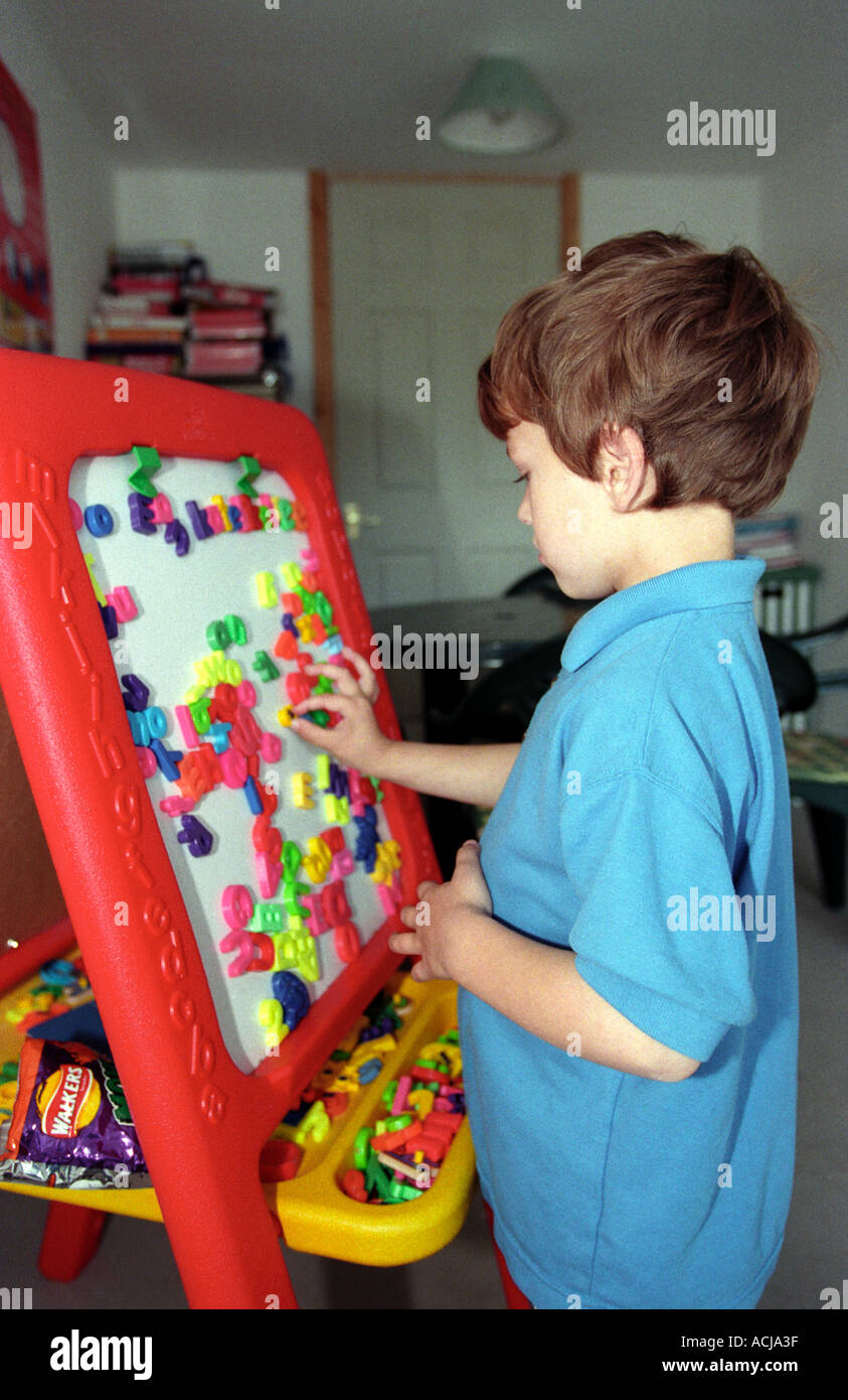 Autistic child playing with coloured lettering (synthetic phonics), Middlesex, England. Stock Photo