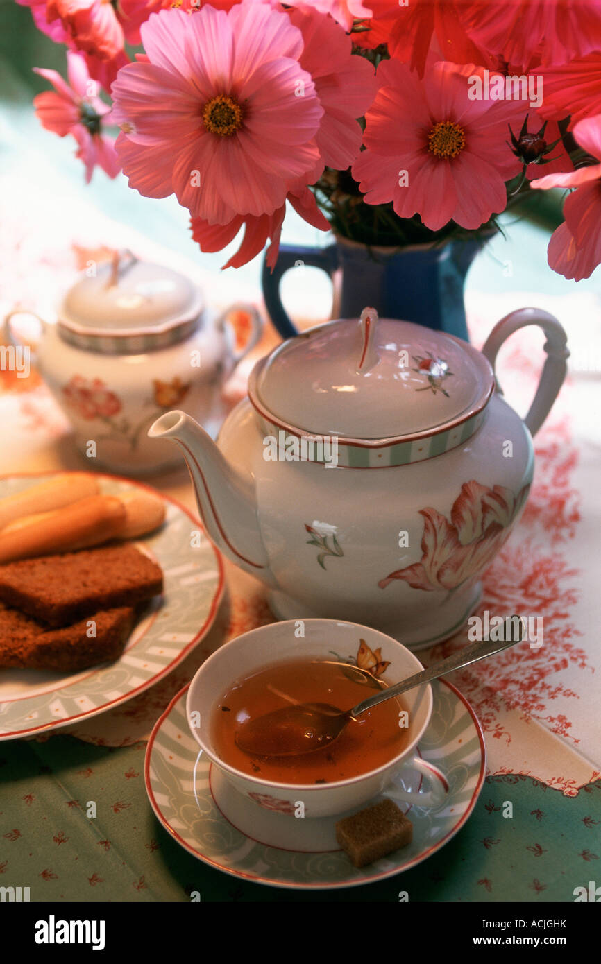 Tea Cup And Tea Pot On Table Bouquet Of Flowers Biscuits In Plate Stock Photo Alamy
