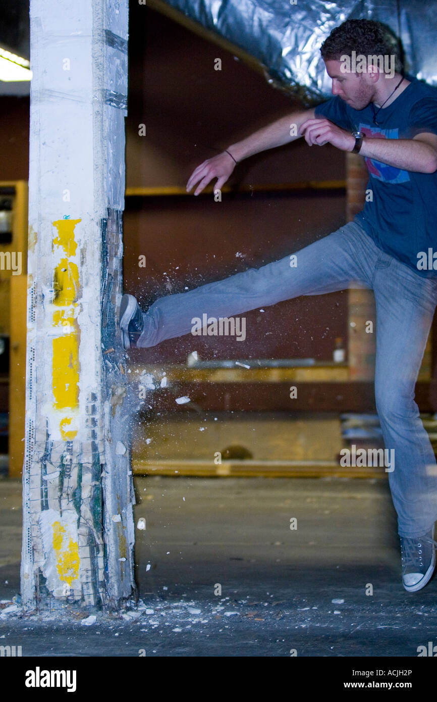 young male man teenager kicking brick wall concrete post pillar column
