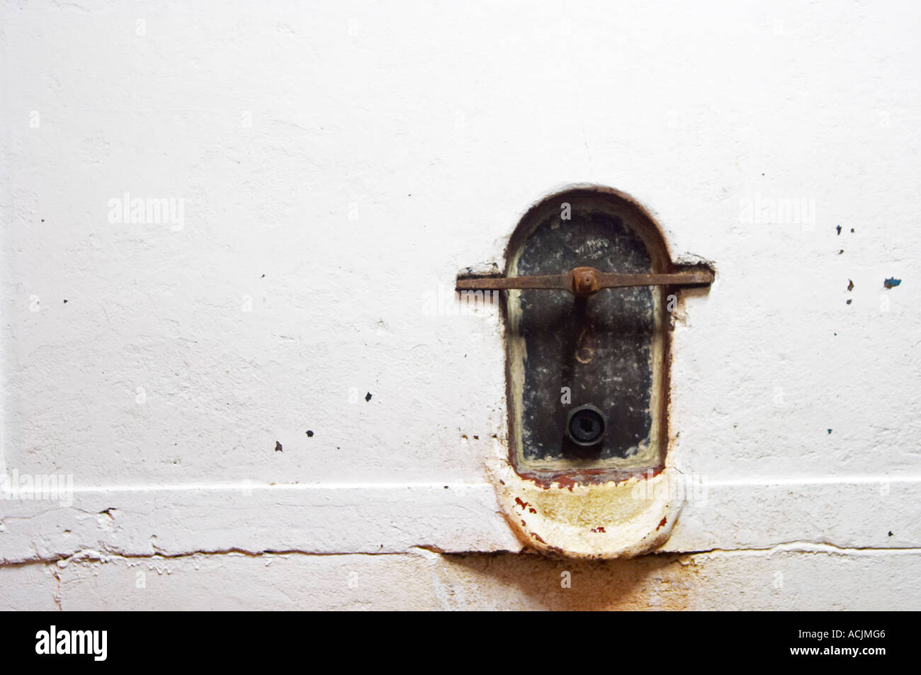 A concrete fermentation vat painted white and with a metal trap door to