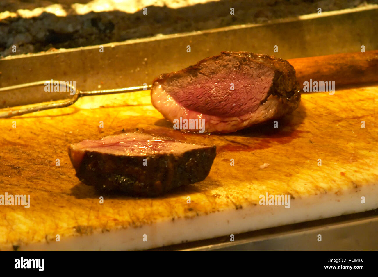 The chef cook carving cutting up a big piece of roast beef with a big