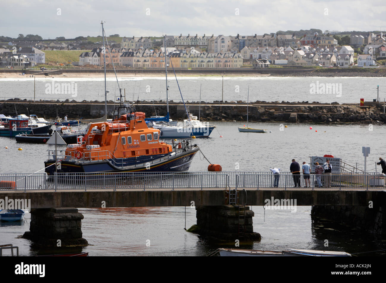 harbour walkway with tourists Portrush lifeboat Katie Hannan Severn class moored in portrush harbour with portrush in background Stock Photo