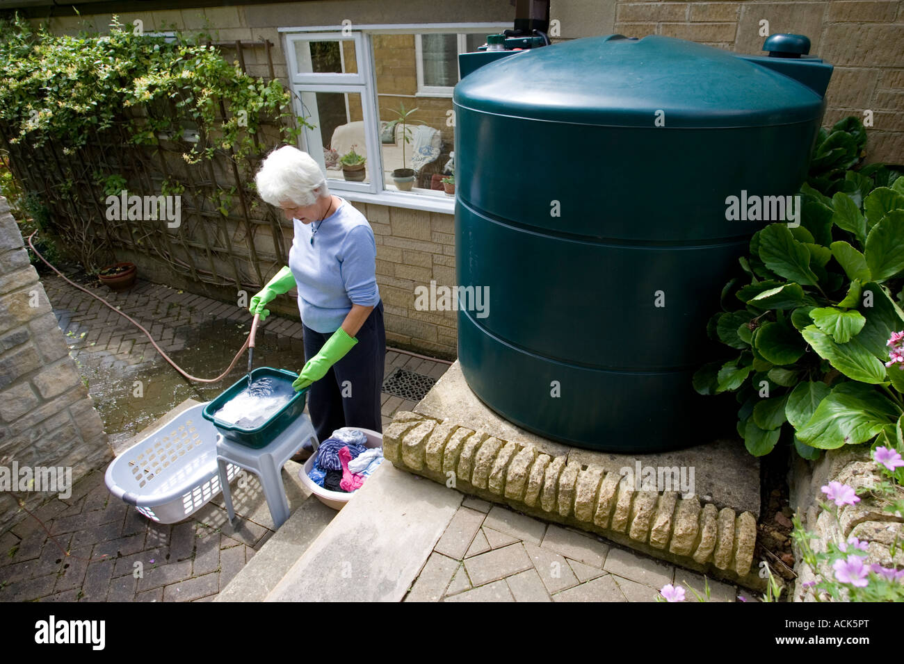 Woman using rainwater from storage tank to wash clothes during water