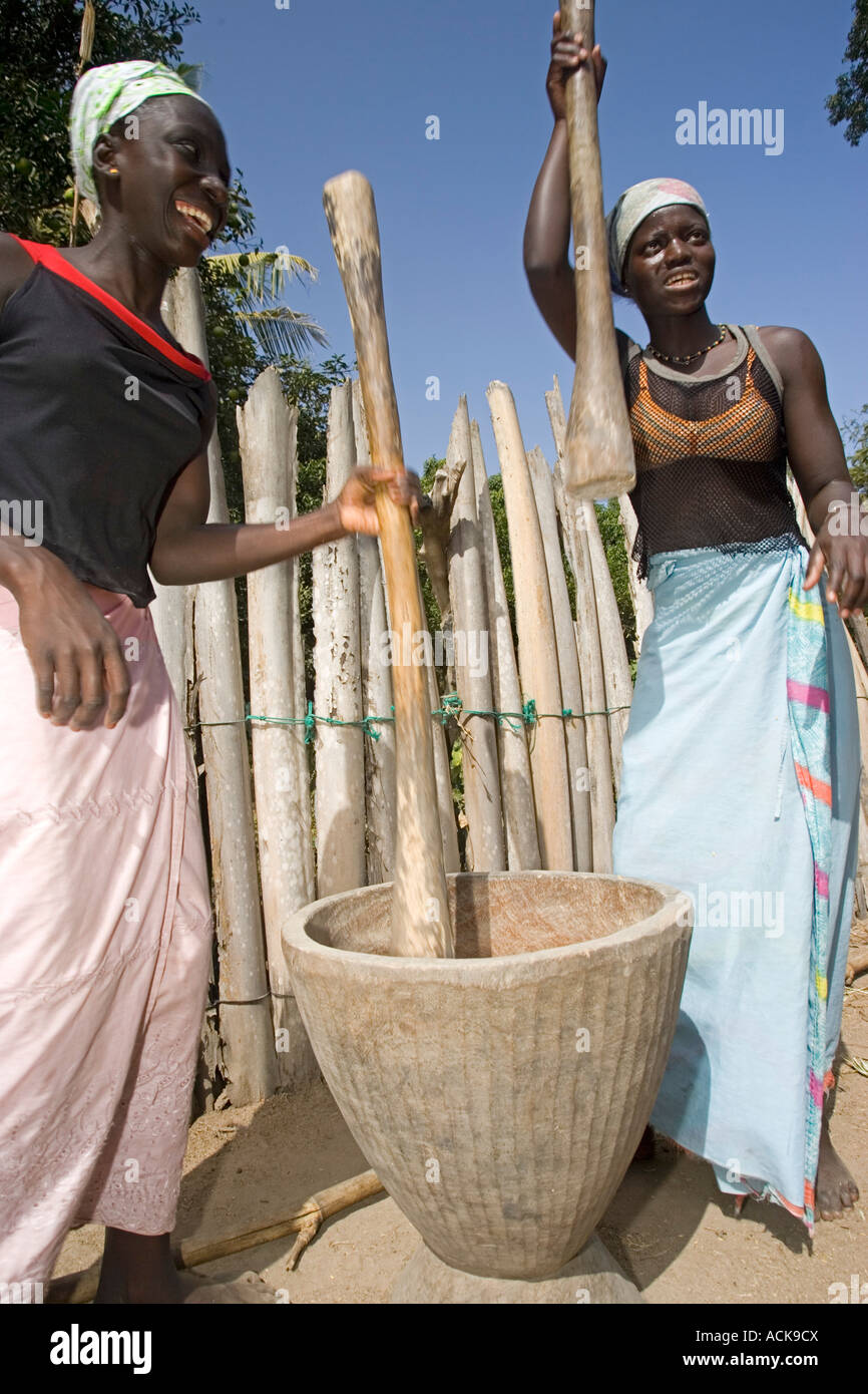 Young women pound rice by hand in wooden pestle and mortar Berending village south of The Gambia Stock Photo