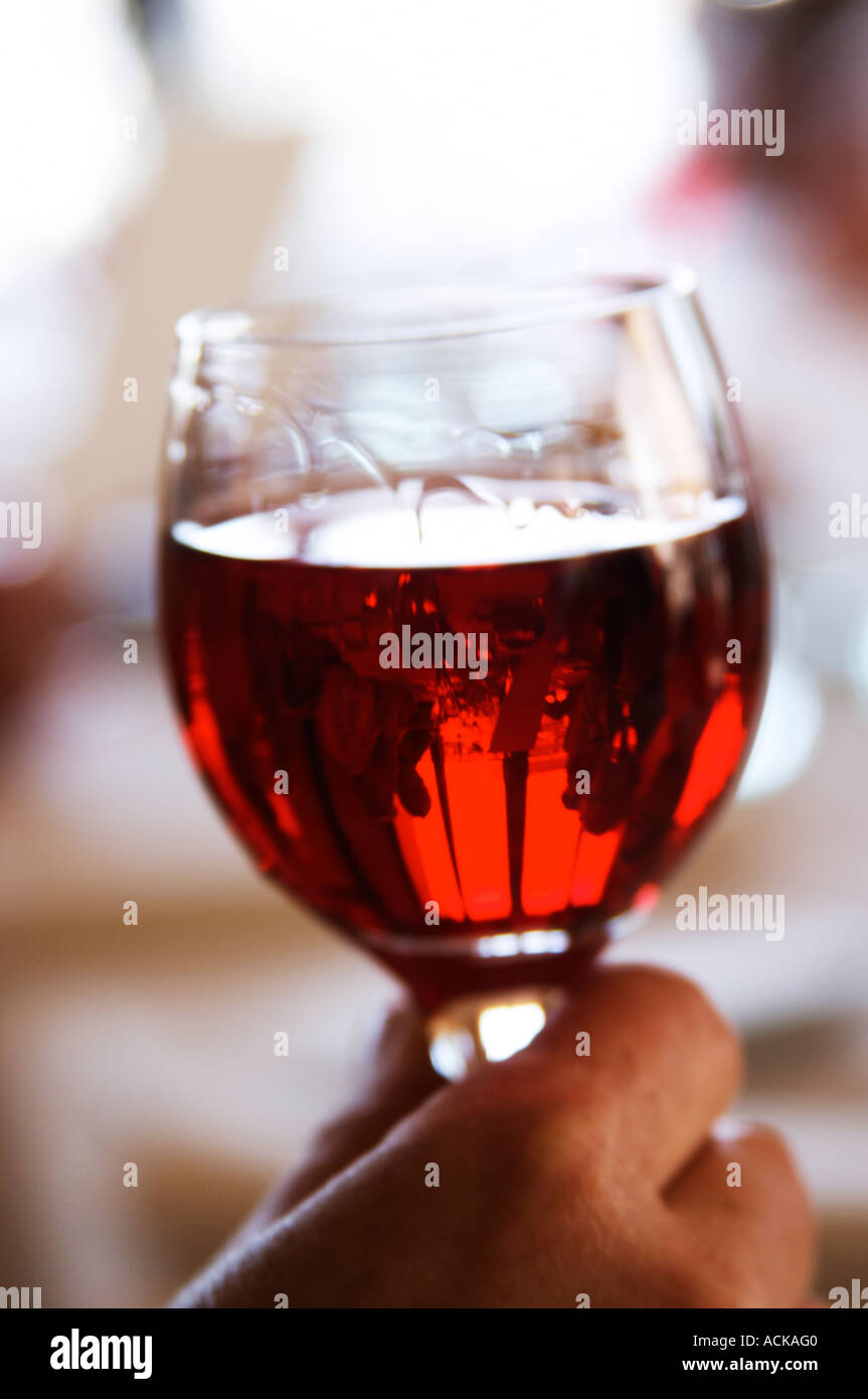 A hand holding a glass of Kir aperitif bright red translucent, in a
