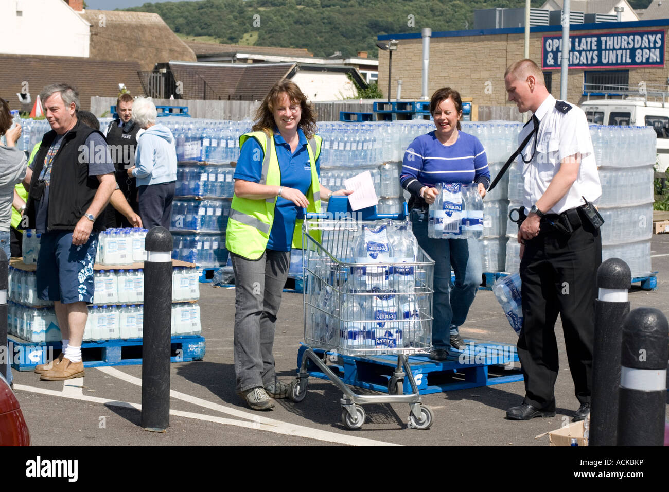 People collecting free bottled water from Tesco car park Bishops Cleeve UK with police on duty Stock Photo