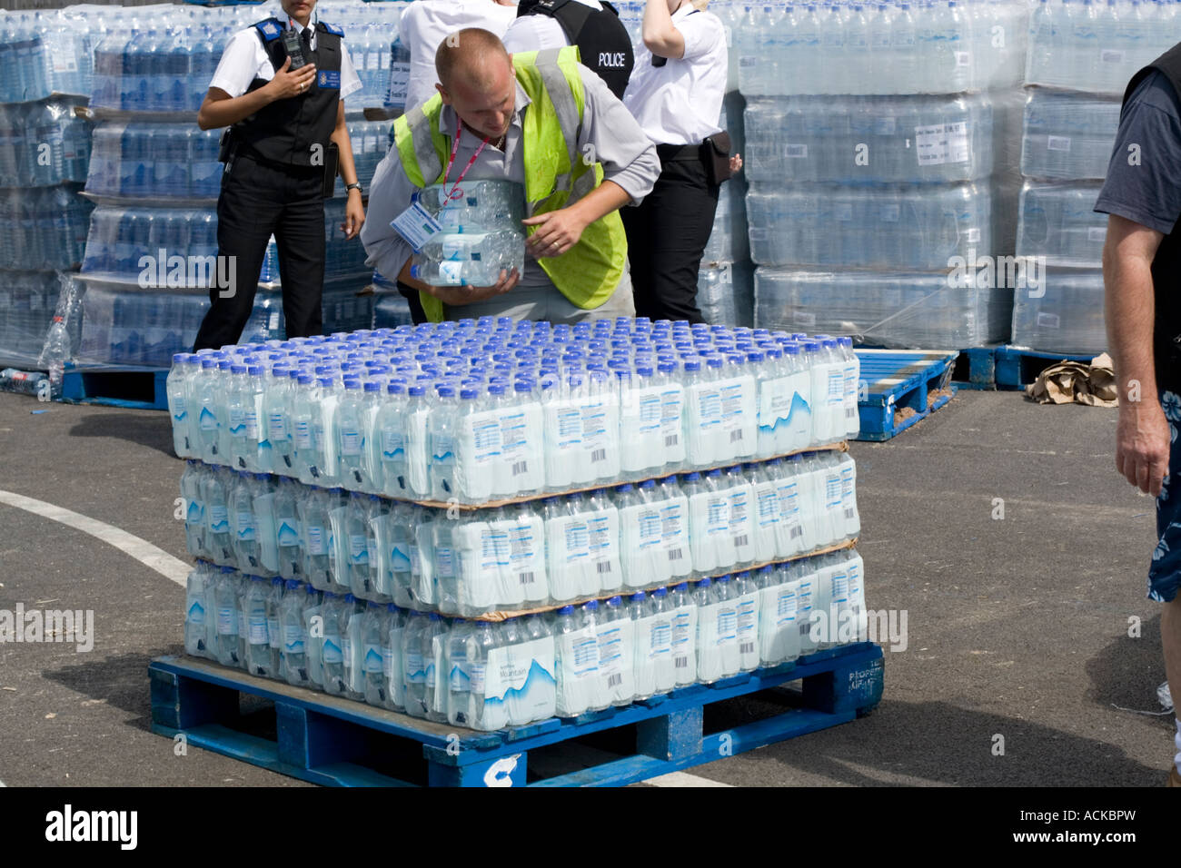Man distributing free bottled water from pallets at Tesco car park