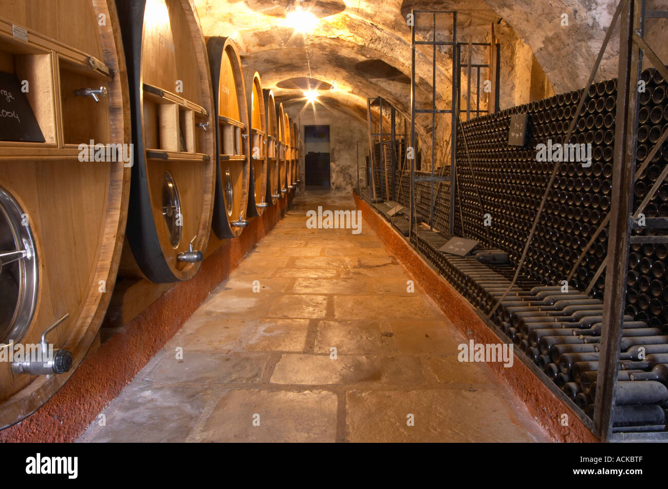Barrels of wine aging in the cellar Piles of old bottles aging in the