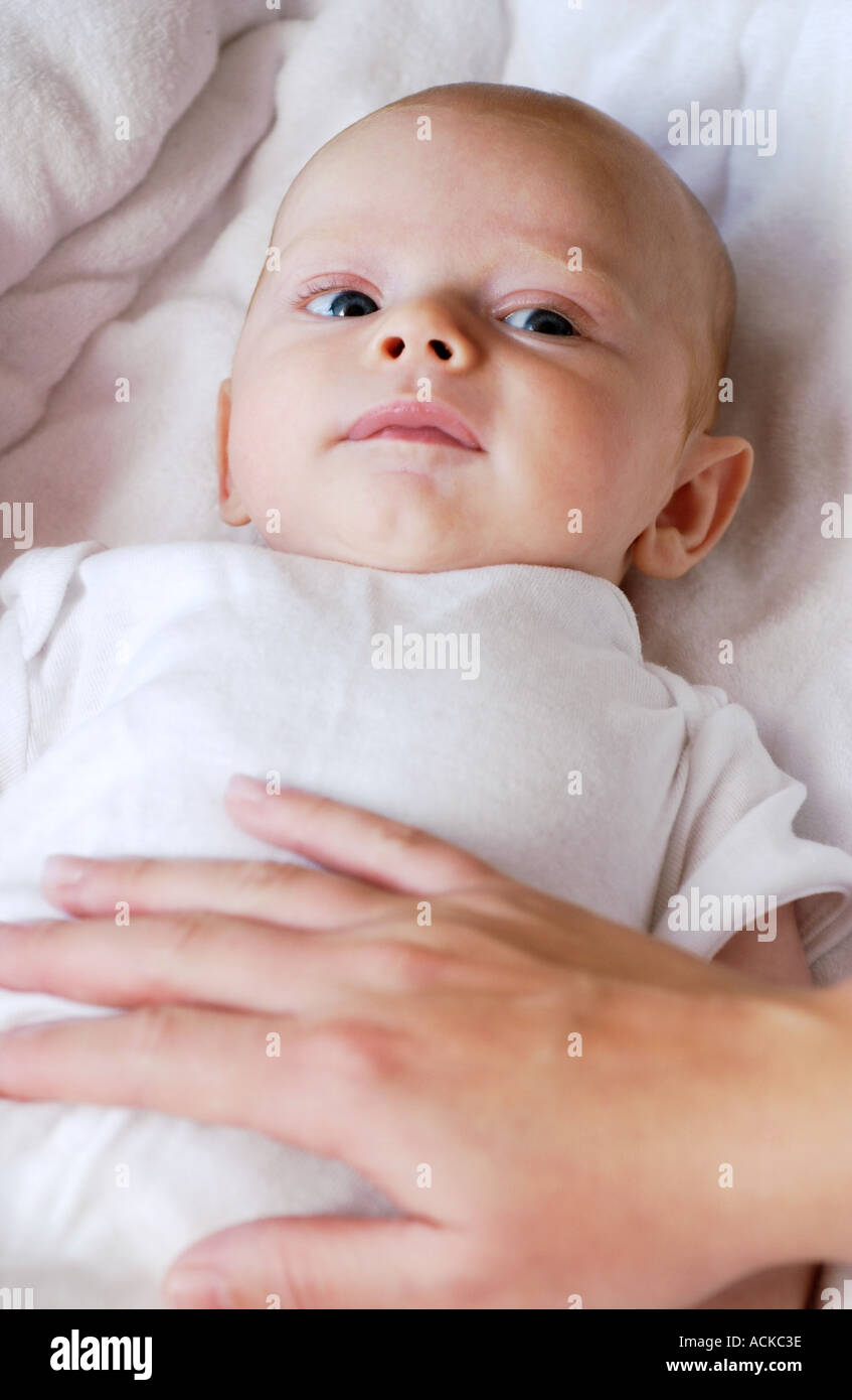 baby laying down with moms hand on stomach Stock Photo Alamy