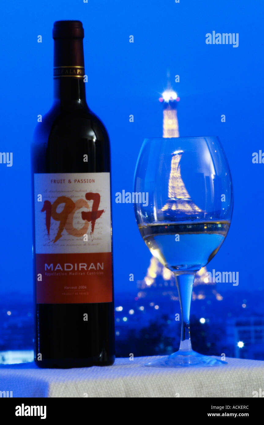 Bottle of 1907 Madiran Fruit and Passion against a dark blue background sky view over Paris with the Eiffel Tower and a glass of wine with a reflection Madiran France Stock Photo