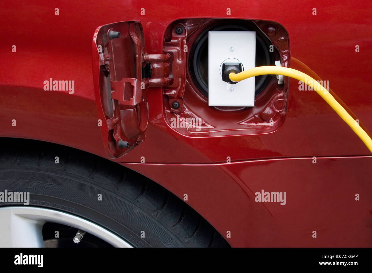 An electrical cord plugged into an outlet inside the gas tank door of a car Stock Photo