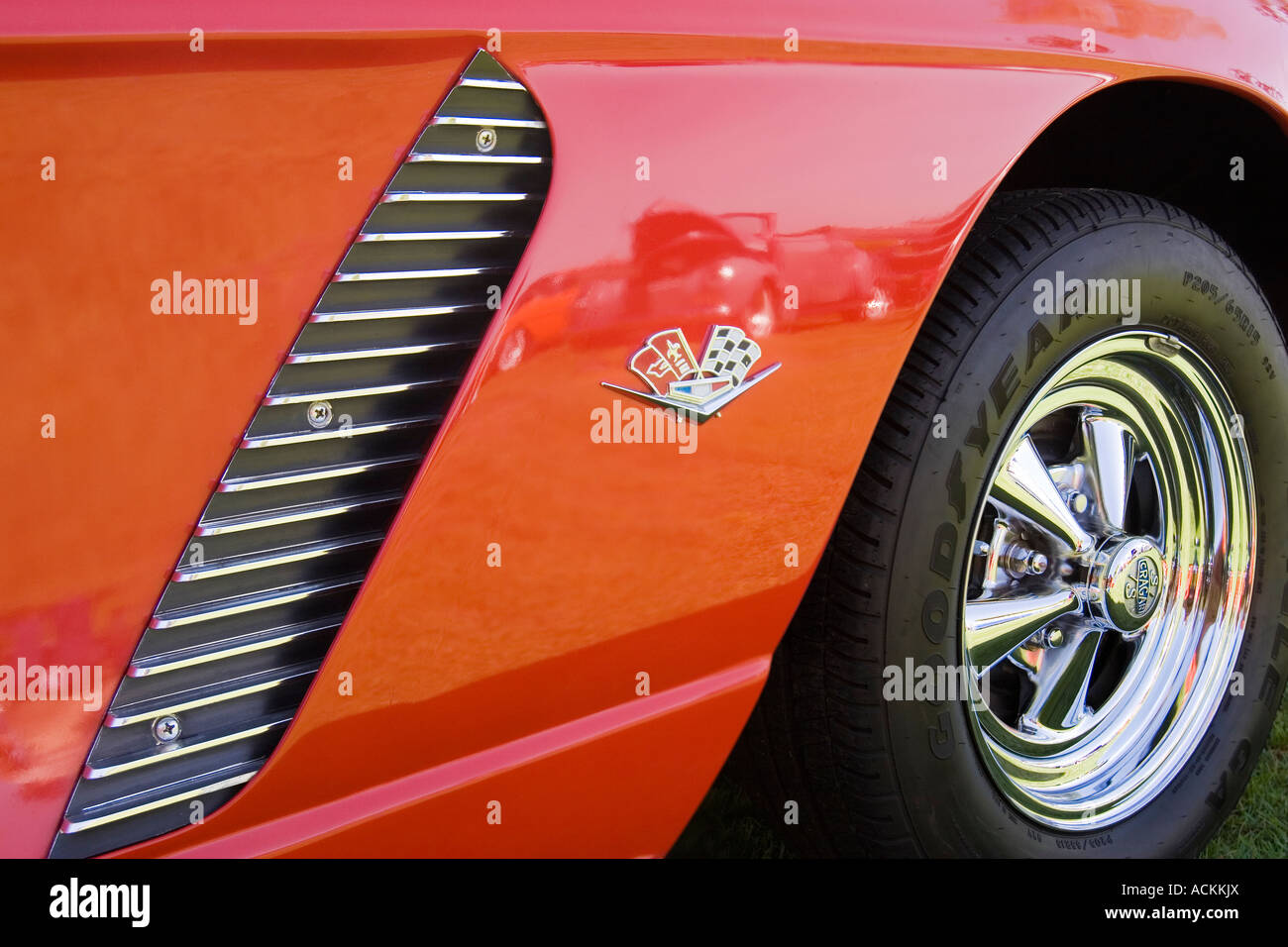 Chrome decoration flags emblem and wheel of a red 1962 Chevrolet Corvette classic car with Goodyear tires at a car show Stock Photo