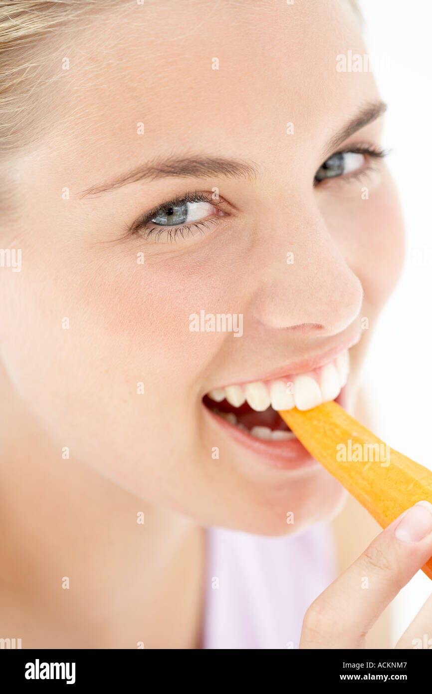 A young woman biting a carrot Stock Photo Alamy