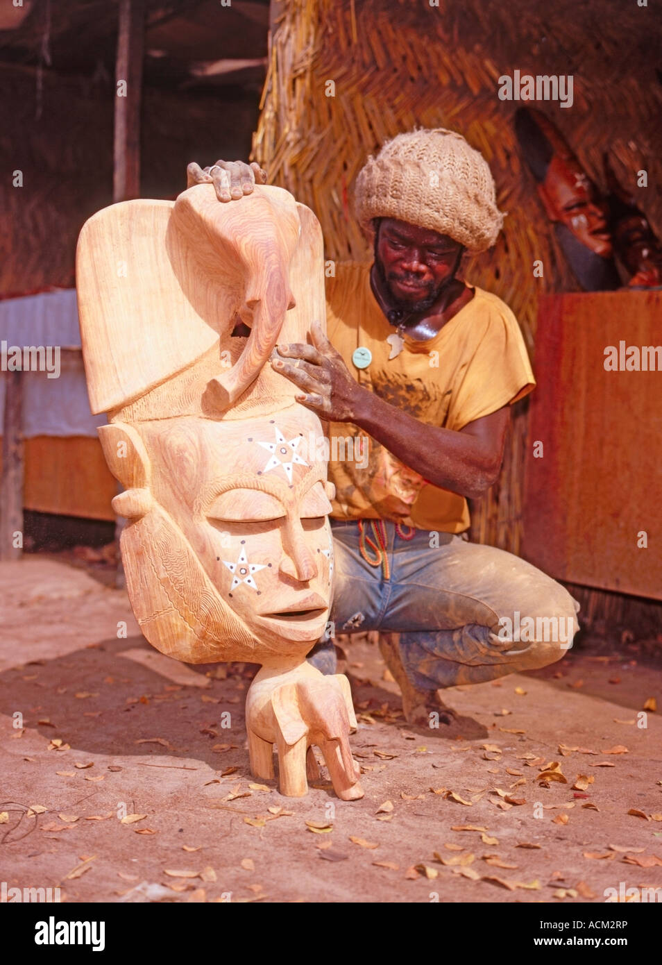Wood carver in The Gambia, West Africa with carved mask souvenir Stock 