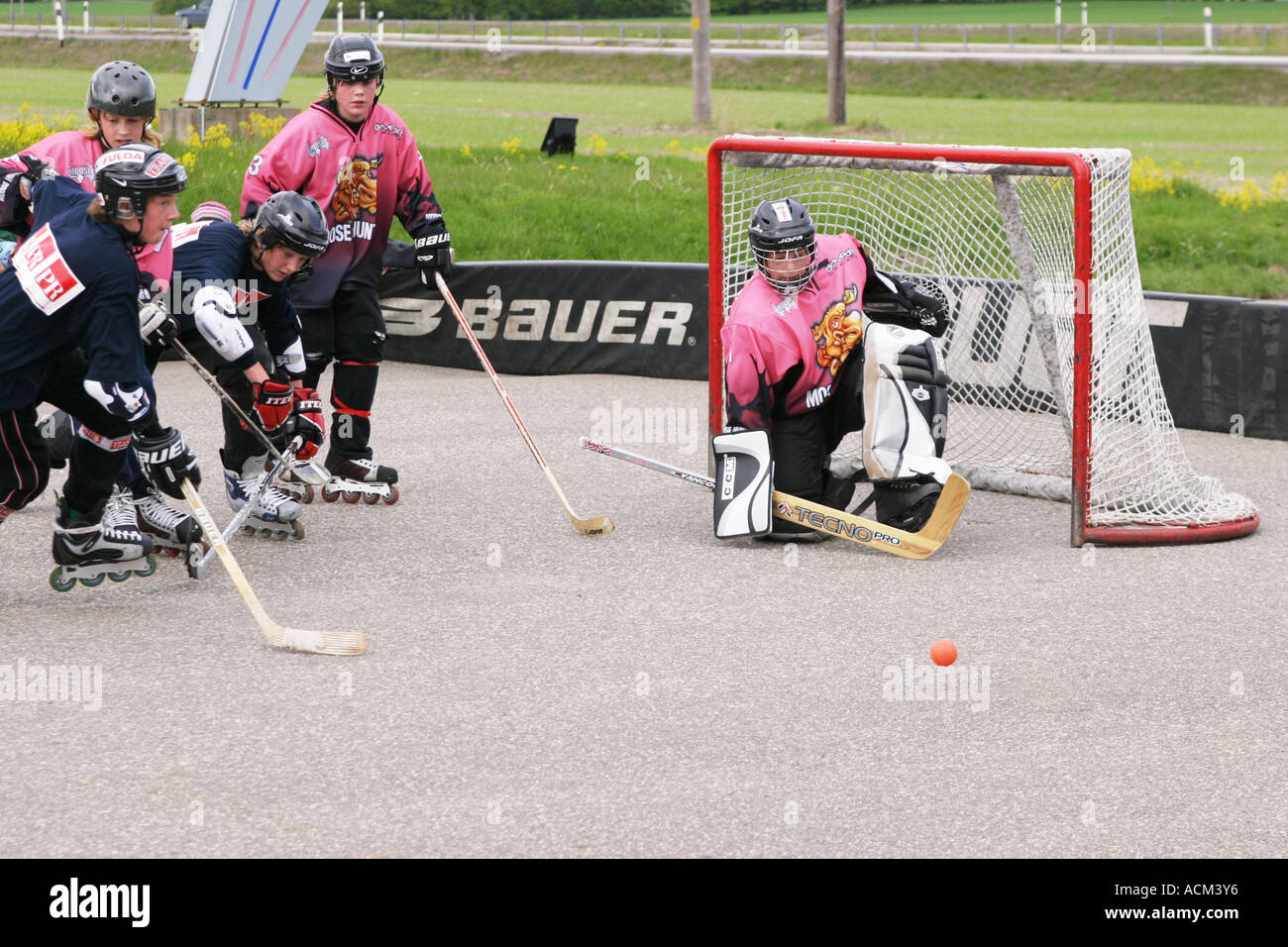 Kids playing street hockey on asphalt with inlines, hockey sticks and a ball Stock Photo