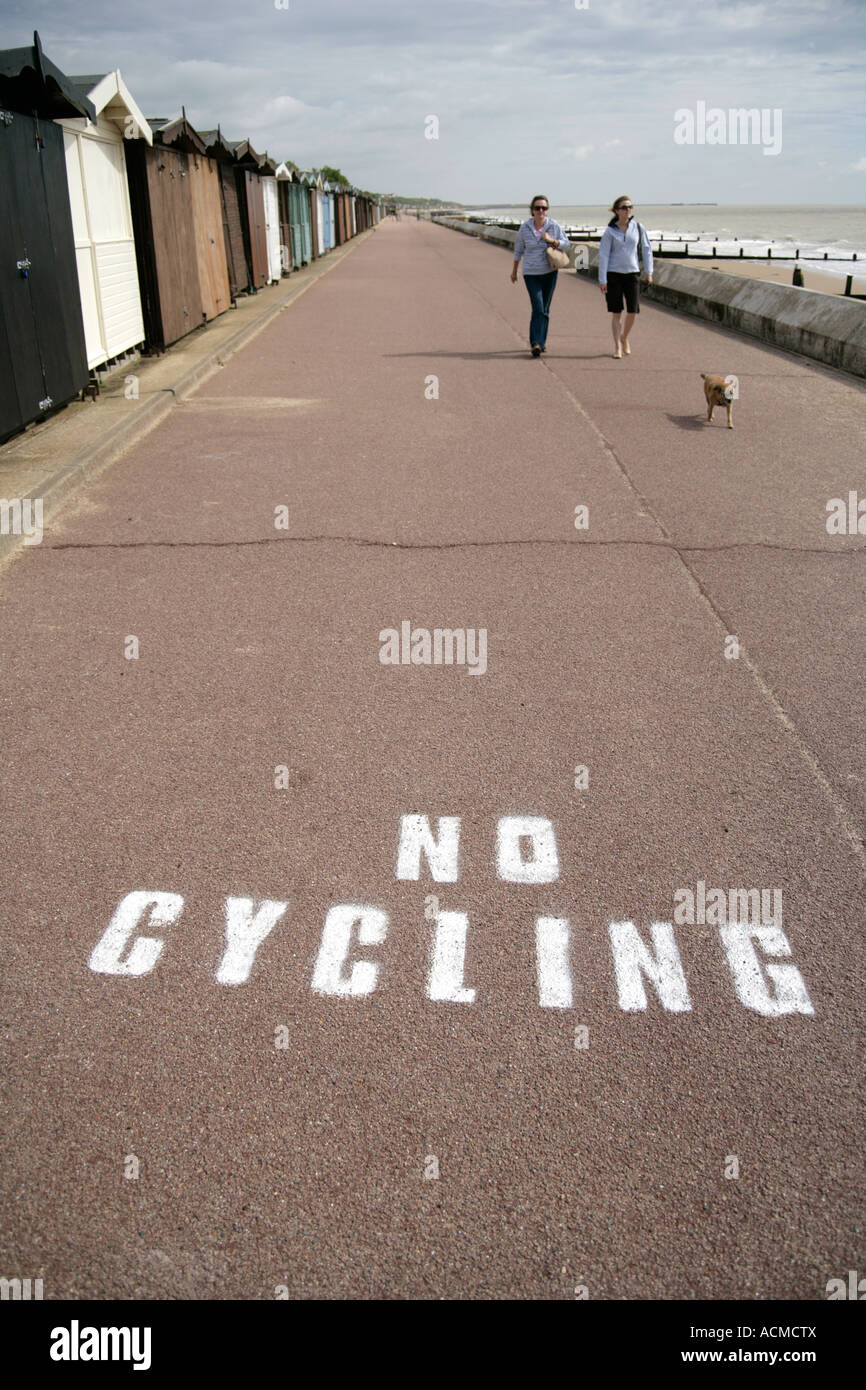 'No Cycling' markings and walkers with dog on the promenade, Frinton on Sea, Essex, England, UK