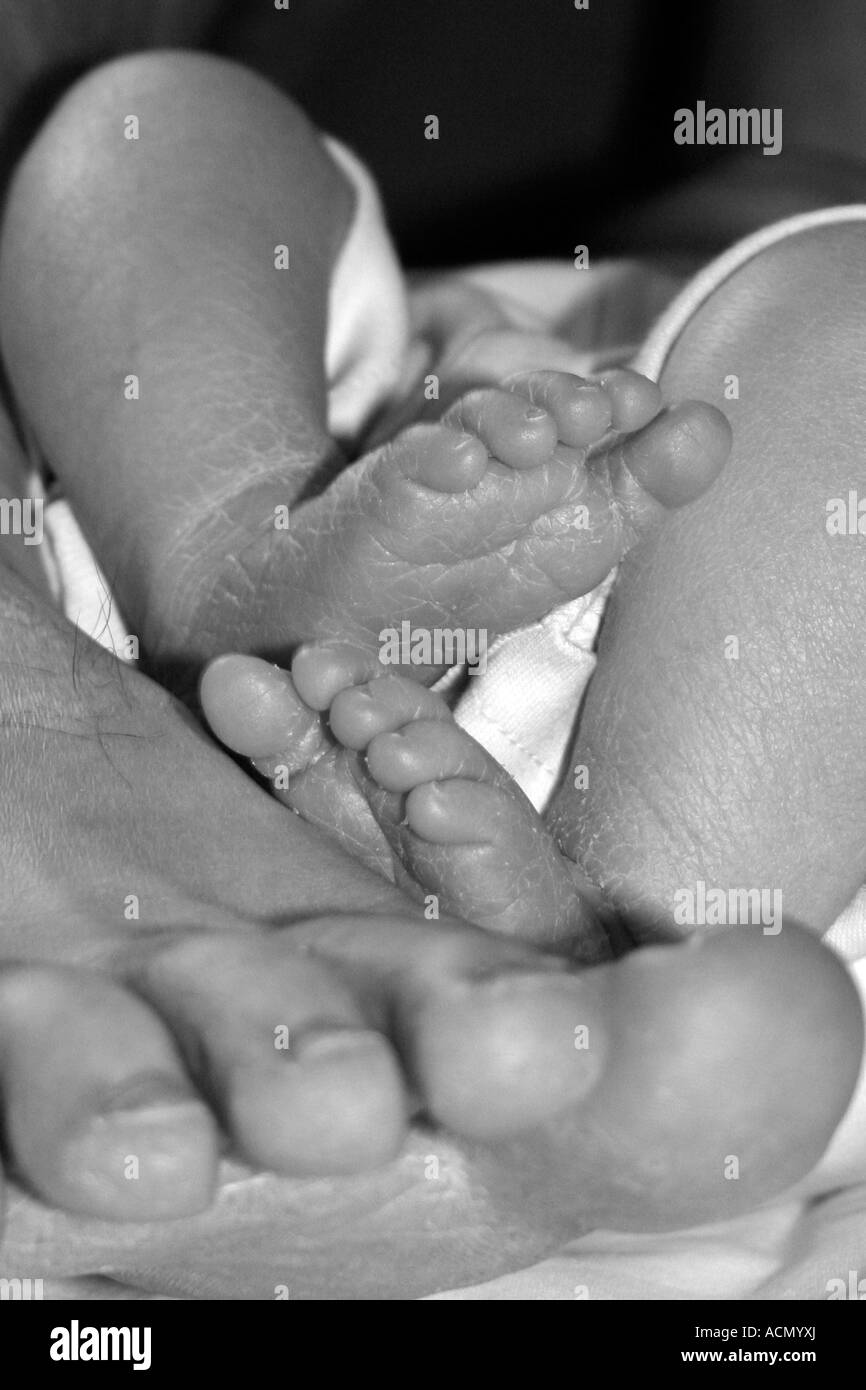 Newborn baby's feet resting on top of his father's foot Stock Photo