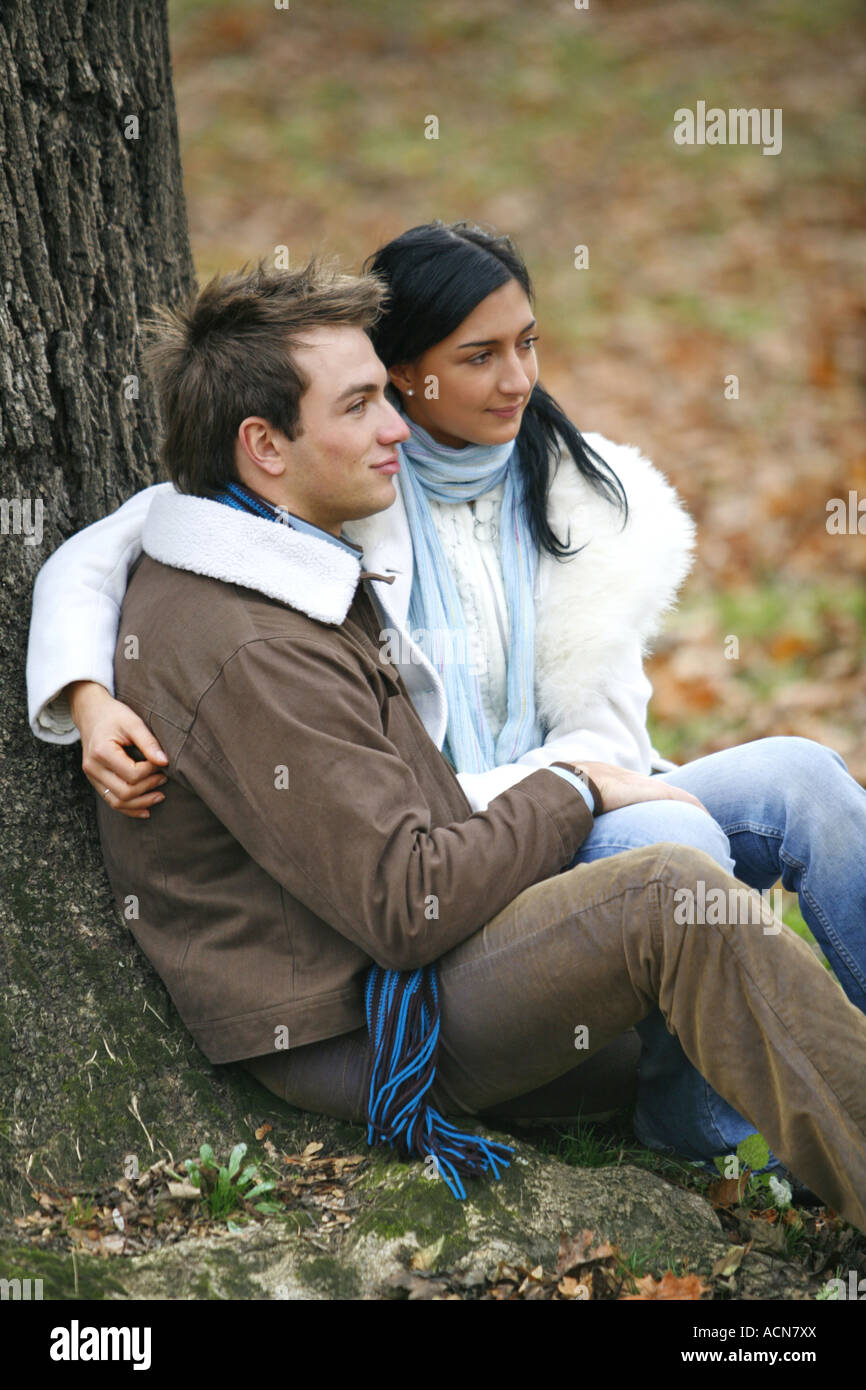 A young couple is sitting on the ground in the autumn forest lifestyle ...