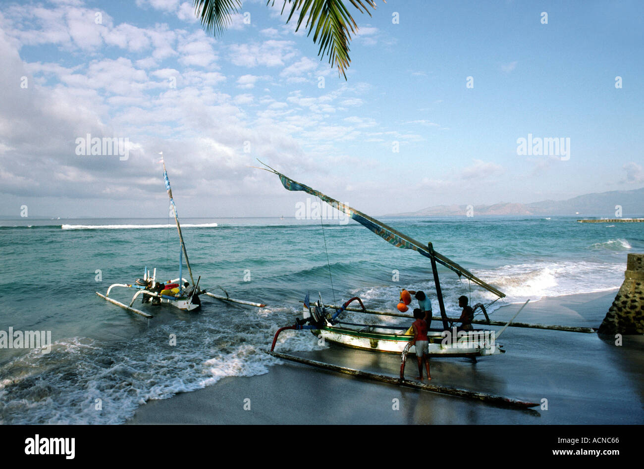 Indonesia Bali Candi Dasa launching fishing boats from beach Stock Photo