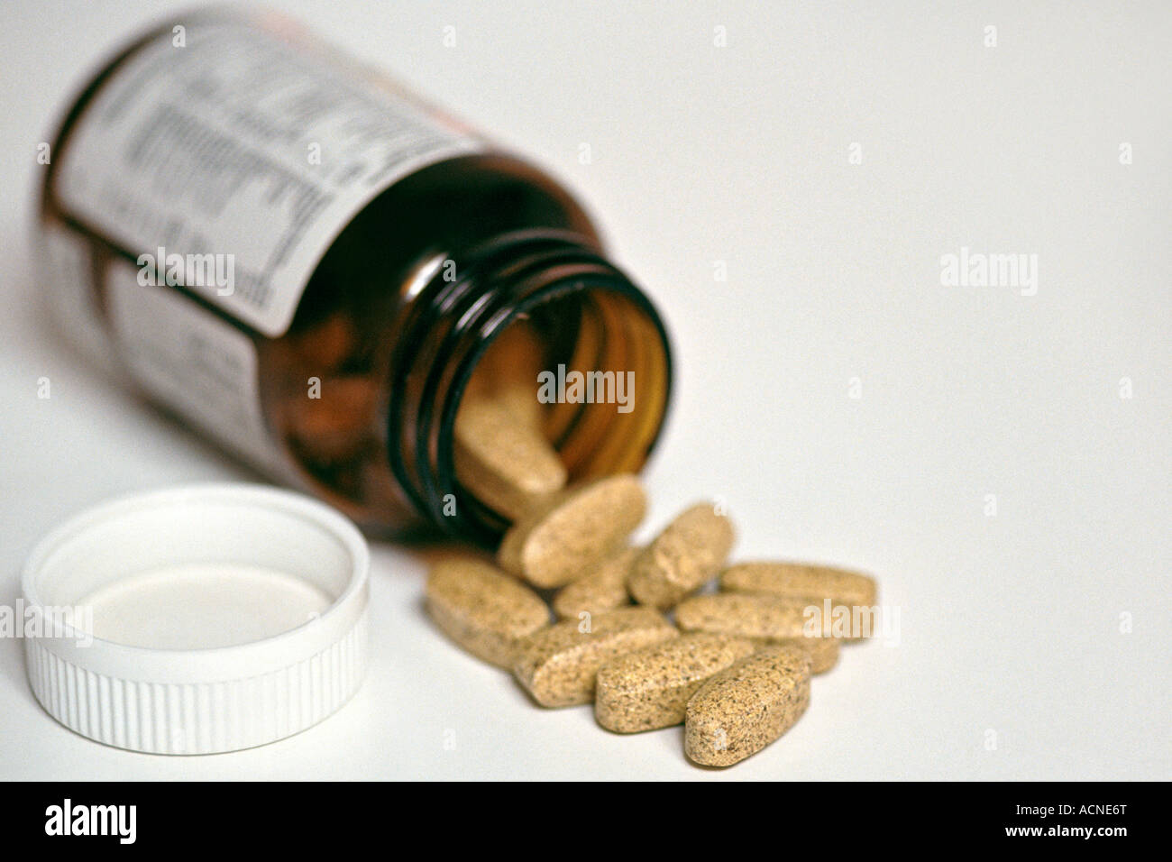 Pill bottle lying open on a white surface with pills spilling out. This image was previously available as image A65B00 or A5WFB9 Stock Photo