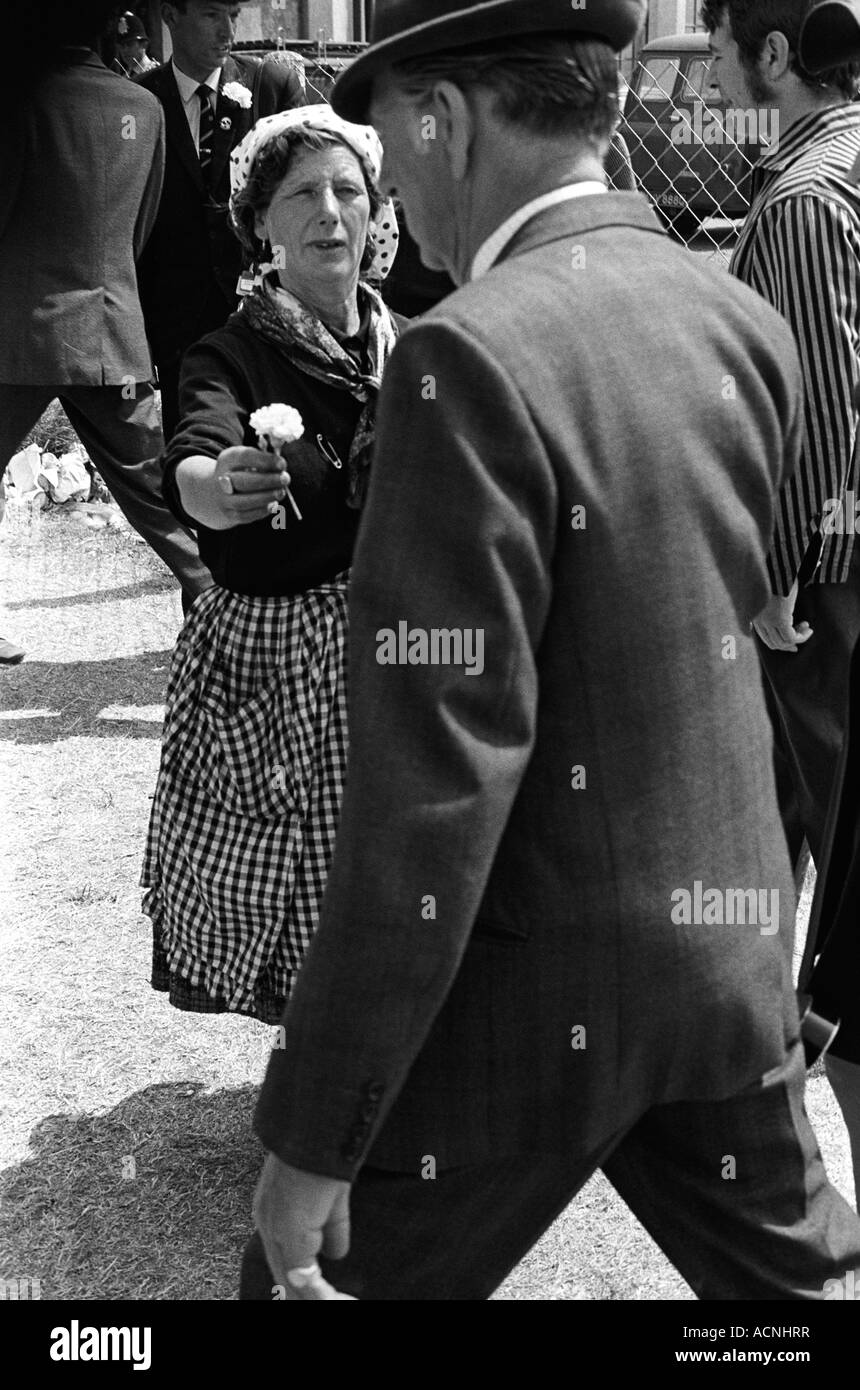 Lucky charms.Gypsy woman selling good luck carnation flowers to race goers Derby Day horse races  Epsom Downs Surrey England 1970 1970s UK HOMER SYKES Stock Photo