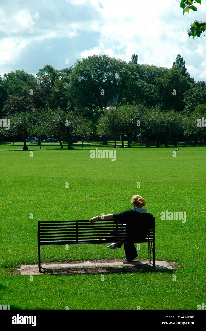 Girl alone on a park bench in The Meadows, Tollcross,Edinburgh,Scotland,UK Stock Photo