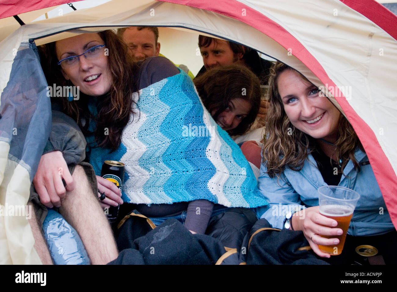 Group of young people camping in small tent Stock Photo