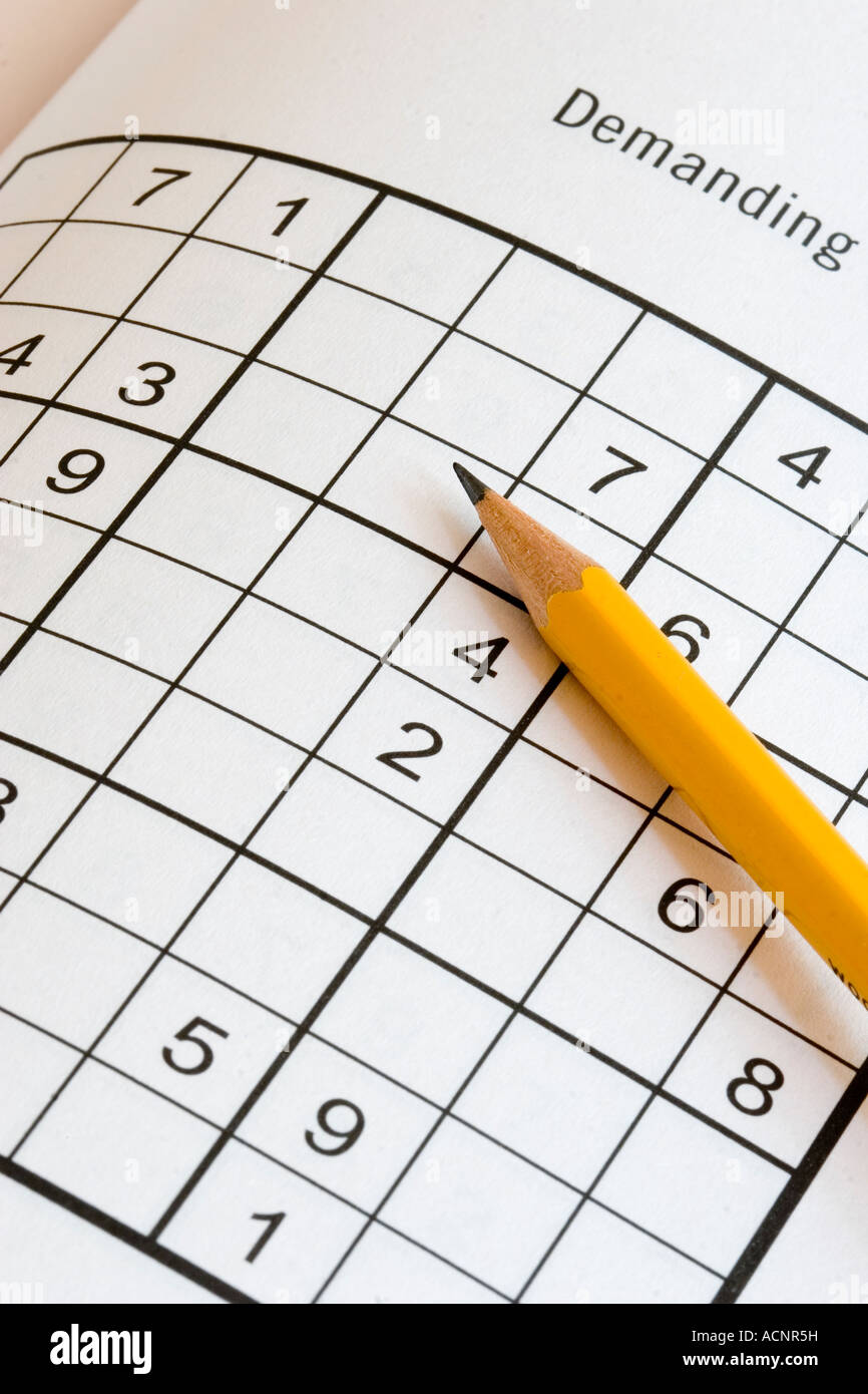 Pencil on a sudoku Japanese number puzzle with the label Demanding indicating how challenging these addictive puzzles can be Stock Photo