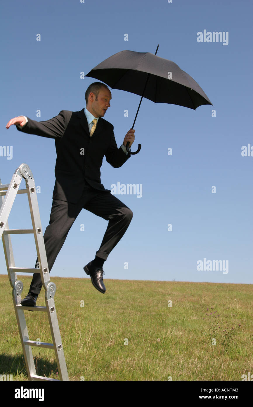 Man jumping from ladder with suit and umbrella - Sprung von einer Leiter mit Anzug und Schirm Stock Photo